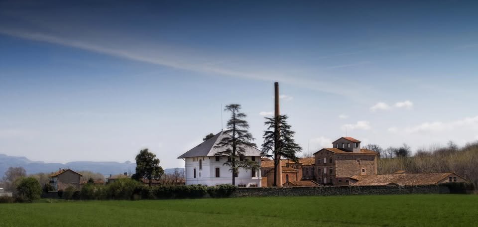 El conjunt de la Colònia Rusiñol amb la xemeneia industrial i el cedre centenari